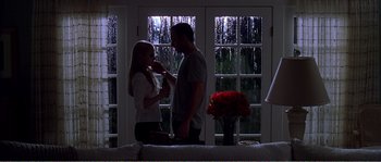 Movie still from “American Beauty” (1999), directed by Sam Mendes – A man and a woman standing next to each other in front of a window; Medium shot, Low angle