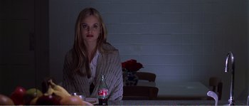 Movie still from “American Beauty” (1999), directed by Sam Mendes – A woman sitting at a table in front of a bottle of soda; Medium shot, Low angle