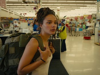 Movie still from “American Honey” (2016), directed by Andrea Arnold – A woman with dreadlocks standing in a store with a backpack; Close Up shot, Over the shoulder angle