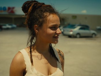 Movie still from “American Honey” (2016), directed by Andrea Arnold – A woman with dreads standing in a parking lot; Close Up shot, Over the shoulder angle