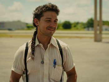 Movie still from “American Honey” (2016), directed by Andrea Arnold – A man with long hair is smiling for the camera; Close Up shot, Over the shoulder angle