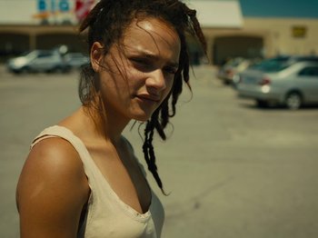 Movie still from “American Honey” (2016), directed by Andrea Arnold – A woman with dreads standing in a parking lot; Close Up shot, High angle