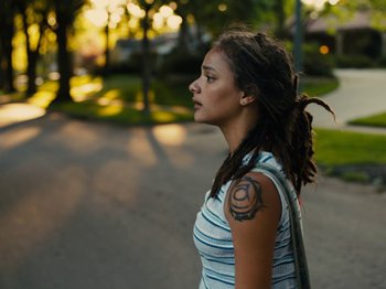 Movie still from “American Honey” (2016), directed by Andrea Arnold – A young woman with dreadlocks standing on the side of the road; Close Up shot, Over the shoulder angle