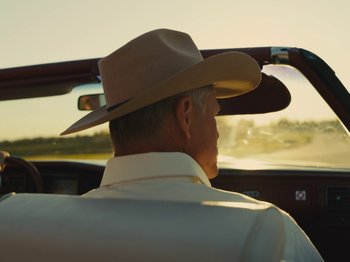 Movie still from “American Honey” (2016), directed by Andrea Arnold – A man wearing a cowboy hat sitting in the back seat of a car; Medium shot, Low angle