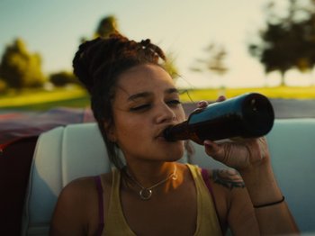 Movie still from “American Honey” (2016), directed by Andrea Arnold – A woman drinking a beer while sitting in a car; Close Up shot, High angle