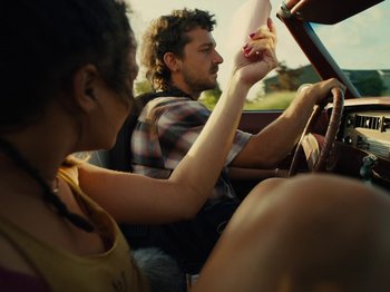 Movie still from “American Honey” (2016), directed by Andrea Arnold – A man and a woman driving a car in the road; Close Up shot, Low angle