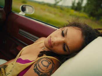 Movie still from “American Honey” (2016), directed by Andrea Arnold – A woman laying in the back seat of a car; Close Up shot, Overhead angle