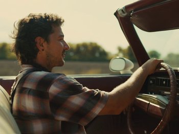 Movie still from “American Honey” (2016), directed by Andrea Arnold – A man driving a car in the sun; Close Up shot, Low angle