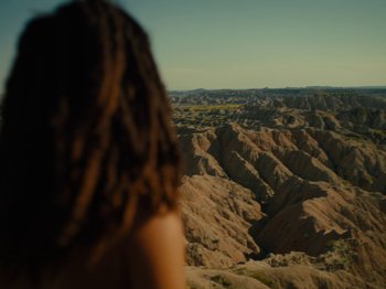 Movie still from “American Honey” (2016), directed by Andrea Arnold – A woman with dreadlocks looking out over a valley; Extreme Wide shot, High angle