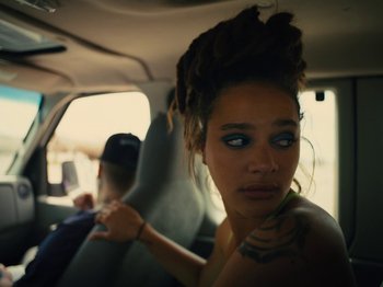 Movie still from “American Honey” (2016), directed by Andrea Arnold – A woman with dreadlocks sitting in the back seat of a car; Close Up shot, High angle