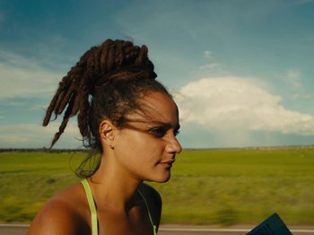Movie still from “American Honey” (2016), directed by Andrea Arnold – A woman with dreads standing in a field; Close Up shot, Over the shoulder angle