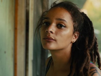 Movie still from “American Honey” (2016), directed by Andrea Arnold – A young woman with long dreadlocks looking into the distance; Close Up shot, Low angle