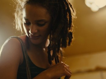 Movie still from “American Honey” (2016), directed by Andrea Arnold – A woman with dreads standing in a room; Close Up shot, Low angle