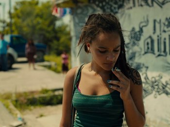 Movie still from “American Honey” (2016), directed by Andrea Arnold – A young woman with dreadlocks talking on a cell phone; Medium shot, High angle