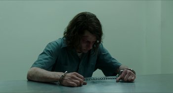 Movie still from “American Ultra” (2015), directed by Nima Nourizadeh – A man in handcuffs sitting at a table; Medium shot, High angle
