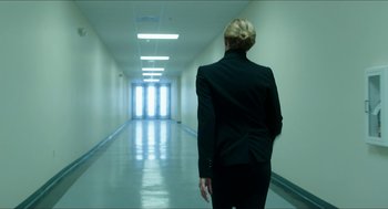 Movie still from “American Ultra” (2015), directed by Nima Nourizadeh – A woman in a black suit walking down a hall way; Wide shot, Low angle