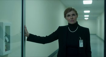 Movie still from “American Ultra” (2015), directed by Nima Nourizadeh – A woman in a black jacket standing next to a white wall; Medium shot, Low angle