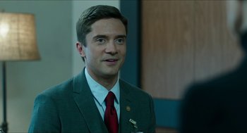 Movie still from “American Ultra” (2015), directed by Nima Nourizadeh – A man in a suit and tie standing next to a wall; Close Up shot, Over the shoulder angle