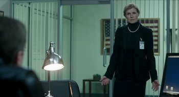 Movie still from “American Ultra” (2015), directed by Nima Nourizadeh – A woman standing in front of a lamp in an office; Medium shot, Low angle