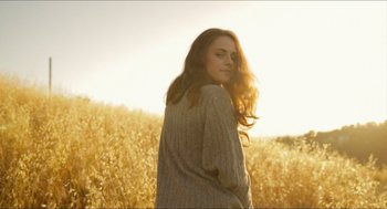 Movie still from “American Ultra” (2015), directed by Nima Nourizadeh – A beautiful young lady standing in front of a field; Medium shot, Low angle