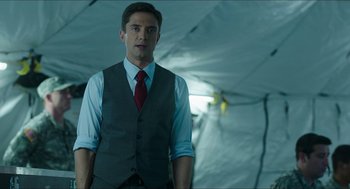 Movie still from “American Ultra” (2015), directed by Nima Nourizadeh – A man wearing a suit and tie standing in front of a tarp tent; Medium shot, Low angle