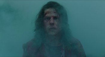 Movie still from “American Ultra” (2015), directed by Nima Nourizadeh – A man with long dark hair and a red shirt is in the fog; Medium shot, Low angle