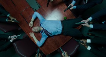 Movie still from “American Ultra” (2015), directed by Nima Nourizadeh – A man laying on the floor of a conference room; Wide shot, Overhead angle