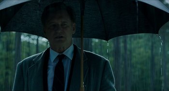 Movie still from “American Ultra” (2015), directed by Nima Nourizadeh – A man holding an umbrella over his head in the rain; Close Up shot, Low angle