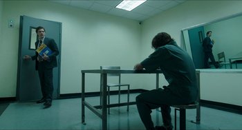 Movie still from “American Ultra” (2015), directed by Nima Nourizadeh – A man sitting at a table in an empty room; Wide shot, Over the shoulder angle
