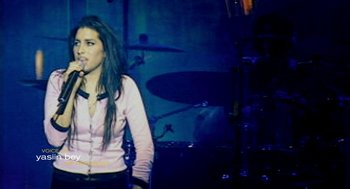 Movie still from “Amy” (2015), directed by Asif Kapadia – A woman standing in front of a drum set on a stage; Medium shot, High angle