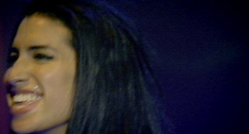 Movie still from “Amy” (2015), directed by Asif Kapadia – A woman with long black hair is looking into the camera; Extreme Close Up shot, Low angle