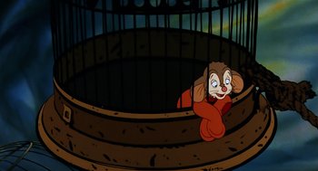 Movie still from “An American Tail” (1986), directed by Don Bluth – An animated picture of an animal sitting in a cage; Medium shot, High angle