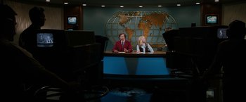 Movie still from “Anchorman 2: The Legend Continues” (2013), directed by Adam McKay – A man and a woman sitting at a desk in front of a globe; Wide shot, High angle