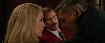 Movie still from “Anchorman 2: The Legend Continues” (2013), directed by Adam McKay – Two men and a woman in a red suit; Close Up shot, Over the shoulder angle