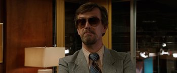Movie still from “Anchorman 2: The Legend Continues” (2013), directed by Adam McKay – A person wearing a suit and sunglasses; Close Up shot, Over the shoulder angle