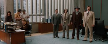 Movie still from “Anchorman 2: The Legend Continues” (2013), directed by Adam McKay – A group of men in suits standing in a room; Wide shot, Low angle
