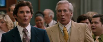 Movie still from “Anchorman 2: The Legend Continues” (2013), directed by Adam McKay – A man in a suit and a yellow neck tie standing next to another man in a suit; Close Up shot, Over the shoulder angle
