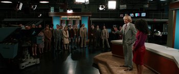 Movie still from “Anchorman 2: The Legend Continues” (2013), directed by Adam McKay – A group of men in suits and ties standing in front of a news anchor; Wide shot, High angle