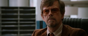 Movie still from “Anchorman 2: The Legend Continues” (2013), directed by Adam McKay – An older man wearing a suit and glasses; Close Up shot, Over the shoulder angle