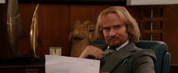Movie still from “Anchorman 2: The Legend Continues” (2013), directed by Adam McKay – A man in a suit and tie holding a pen and paper; Close Up shot, Over the shoulder angle