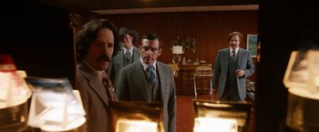 Movie still from “Anchorman 2: The Legend Continues” (2013), directed by Adam McKay – A group of men standing in a room with lamps; Medium shot, Over the shoulder angle
