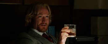 Movie still from “Anchorman 2: The Legend Continues” (2013), directed by Adam McKay – A man in a suit holding up a glass of whiskey; Close Up shot, Over the shoulder angle