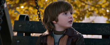 Movie still from “Anchorman 2: The Legend Continues” (2013), directed by Adam McKay – A young boy sitting on top of a wooden bench; Close Up shot, Over the shoulder angle