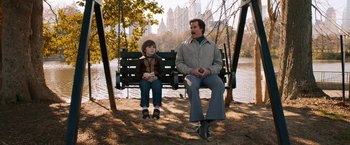 Movie still from “Anchorman 2: The Legend Continues” (2013), directed by Adam McKay – A man sitting on a swing next to a little boy; Wide shot, High angle