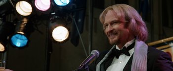 Movie still from “Anchorman 2: The Legend Continues” (2013), directed by Adam McKay – A man with blonde hair is speaking into a microphone; Close Up shot, Over the shoulder angle