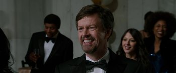 Movie still from “Anchorman 2: The Legend Continues” (2013), directed by Adam McKay – A person wearing a suit and a bow tie; Close Up shot, Over the shoulder angle
