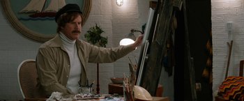 Movie still from “Anchorman 2: The Legend Continues” (2013), directed by Adam McKay – A man standing in front of an easel holding a paintbrush; Medium shot, Over the shoulder angle