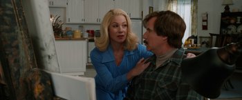 Movie still from “Anchorman 2: The Legend Continues” (2013), directed by Adam McKay – A woman is touching a man's face in a kitchen; Medium shot, Over the shoulder angle