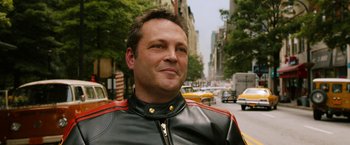 Movie still from “Anchorman 2: The Legend Continues” (2013), directed by Adam McKay – A person wearing a leather jacket on a city street; Close Up shot, Over the shoulder angle