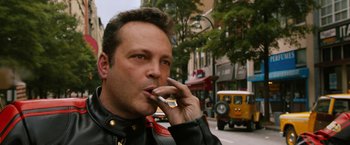 Movie still from “Anchorman 2: The Legend Continues” (2013), directed by Adam McKay – A person smoking a cigarette on the street; Close Up shot, Over the shoulder angle